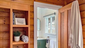 A wooden interior with a bookshelf, a green cabinet, a window, and a towel hanging on the wall. - Cottage # 5 Hunts Point Beach Cottages - 1 bedroom (Hunts Point)