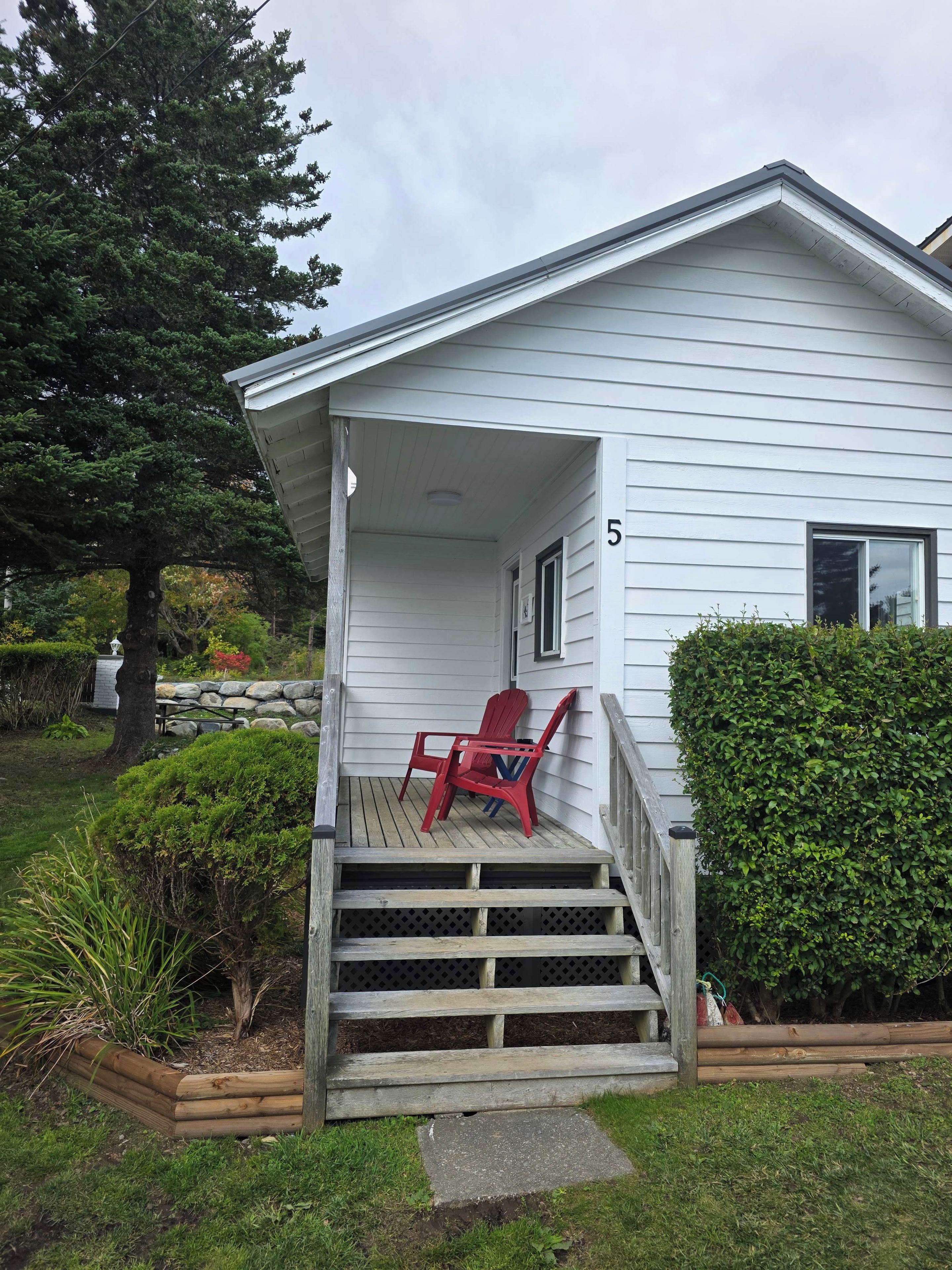 A house with a porch, a number 5 sign, and a red chair.