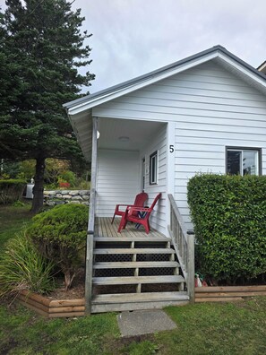Une maison avec un porche, une plaque portant le numéro 5 et une chaise rouge.