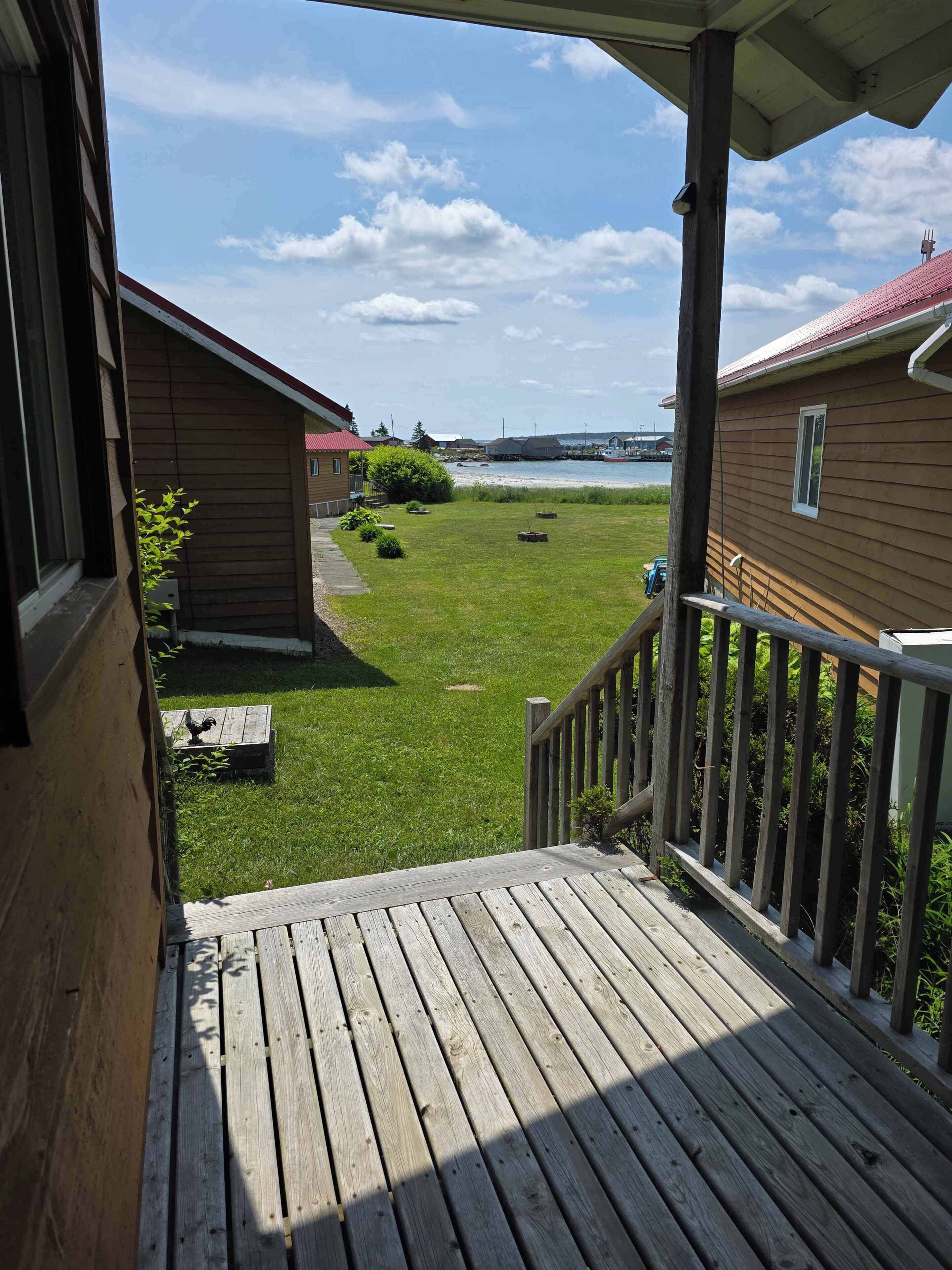 A wooden deck with a view of a grassy yard and a body of water.