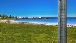 A grassy field, a wooden fence, and a clear blue sky. - Cottage # 9 Hunts Point Beach Cottages - 1 bedroom (Hunts Point)