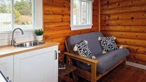A cabin interior with a wooden interior, a sink, a sofa, and a window. - Cottage # 9 Hunts Point Beach Cottages - 1 bedroom (Hunts Point)