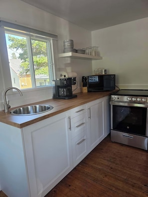 A modern kitchen with a stainless steel sink, a coffee maker, a microwave, and a built-in oven.