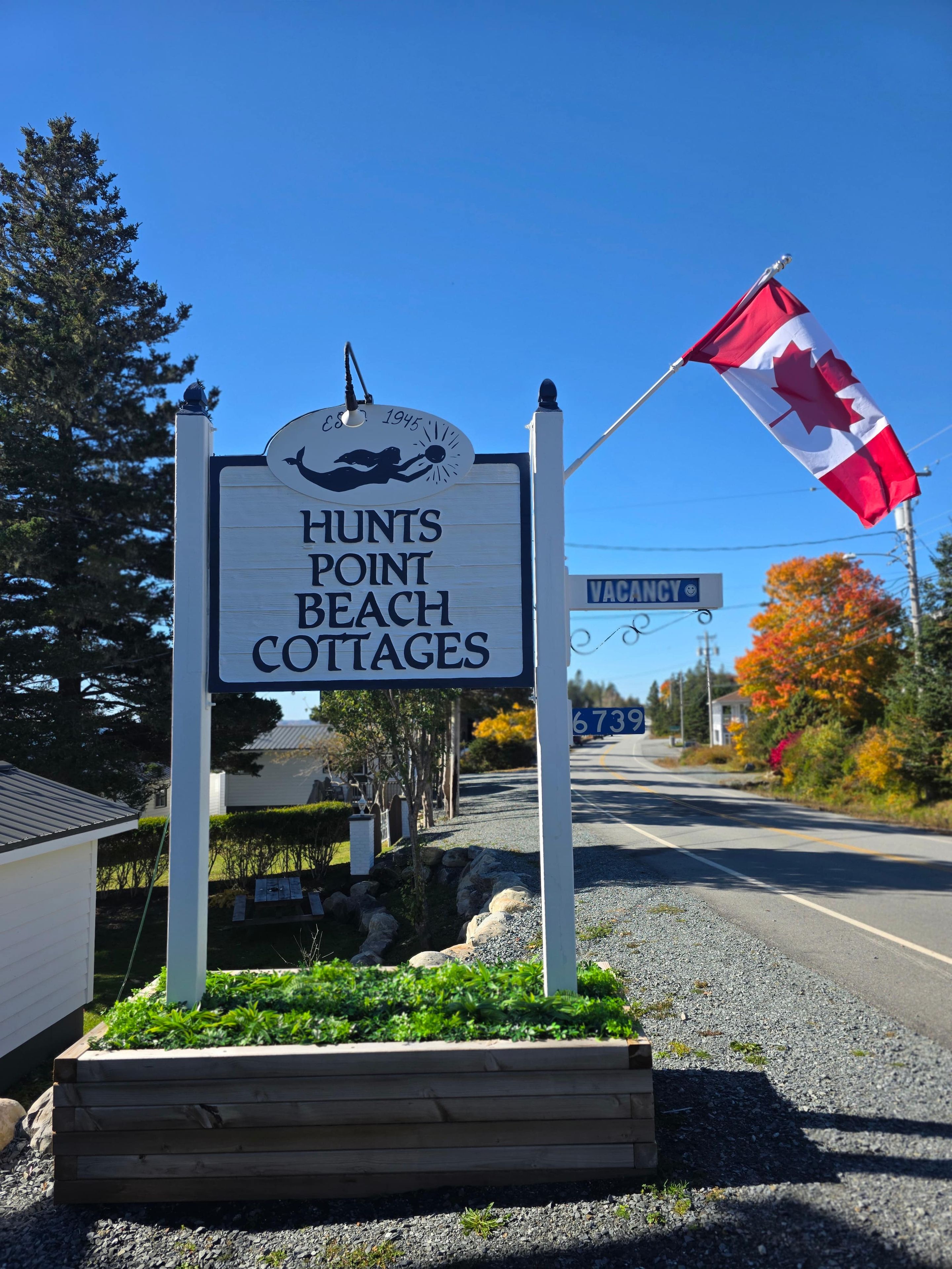 A sign for Hunts Point Beach Cottages with a flag.