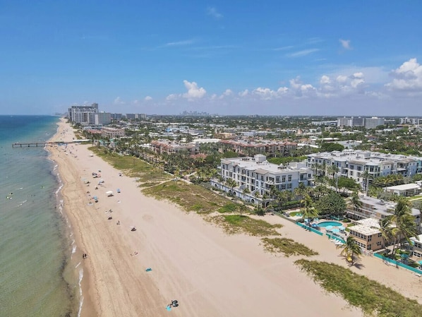Une station balnéaire dotée de logements situés en bord de mer, d’une piscine et d’une jetée qui s’avance dans l’océan.