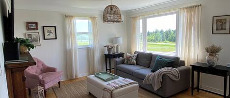 A spacious living room with a sofa, armchair, ottoman, and a coffee table.
