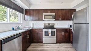Een moderne keuken met donkere houten kastjes, roestvrijstalen apparatuur en een granieten aanrecht.