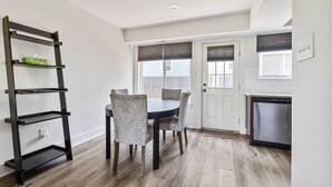Een eethoek met een tafel en stoelen, een laddenplank, een deur en een keuken met een vaatwasser.