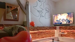 A living room with a brick wall, a television, and a sofa.