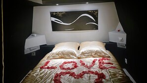 A bedroom with a bed, a wall-mounted artwork, and a nightstand.