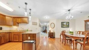 A spacious kitchen with wooden cabinets, a stainless steel refrigerator, and pendant lighting. - Spacious 1 king bedroom WiFi on-site restaurant (Moneta)