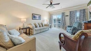 A spacious living room with a sofa, a chair, a table, and a ceiling fan. - Spacious 1 king bedroom WiFi on-site restaurant (Moneta)