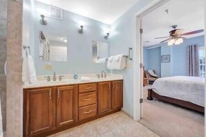 Une salle de bain avec un meuble-lavabo à deux vasques, un miroir et un ventilateur de plafond.