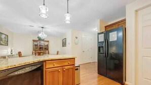 A kitchen with wooden cabinets, a stainless steel refrigerator, and pendant lighting. - Spacious 1 king bedroom WiFi on-site restaurant (Moneta)