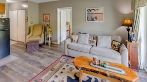 A living room with a sofa, a wooden coffee table, a patterned rug, and a painting on the wall. - Mountainside Condo at Loon (Lincoln)
