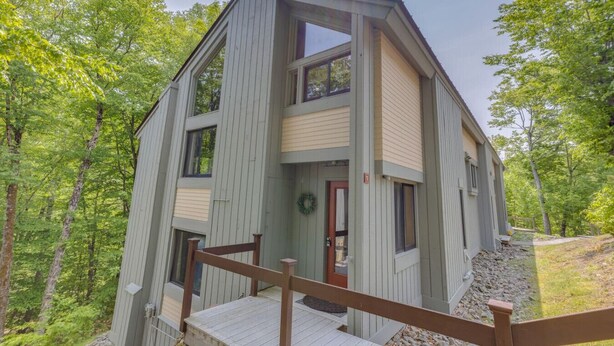 A two-story cabin with a wooden deck and a front door. - Dog Friendly Condo at Clearbrook (Lincoln)