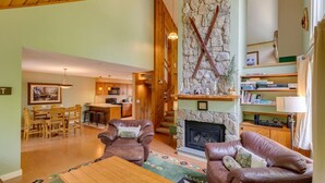 A spacious living room with a stone fireplace, leather sofas, a dining area with wooden chairs, and a kitchen in the background. - Dog Friendly Condo at Clearbrook (Lincoln)