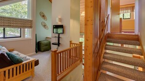 A bedroom with a bed, a suitcase, a television, and a staircase. - Dog Friendly Condo at Clearbrook (Lincoln)