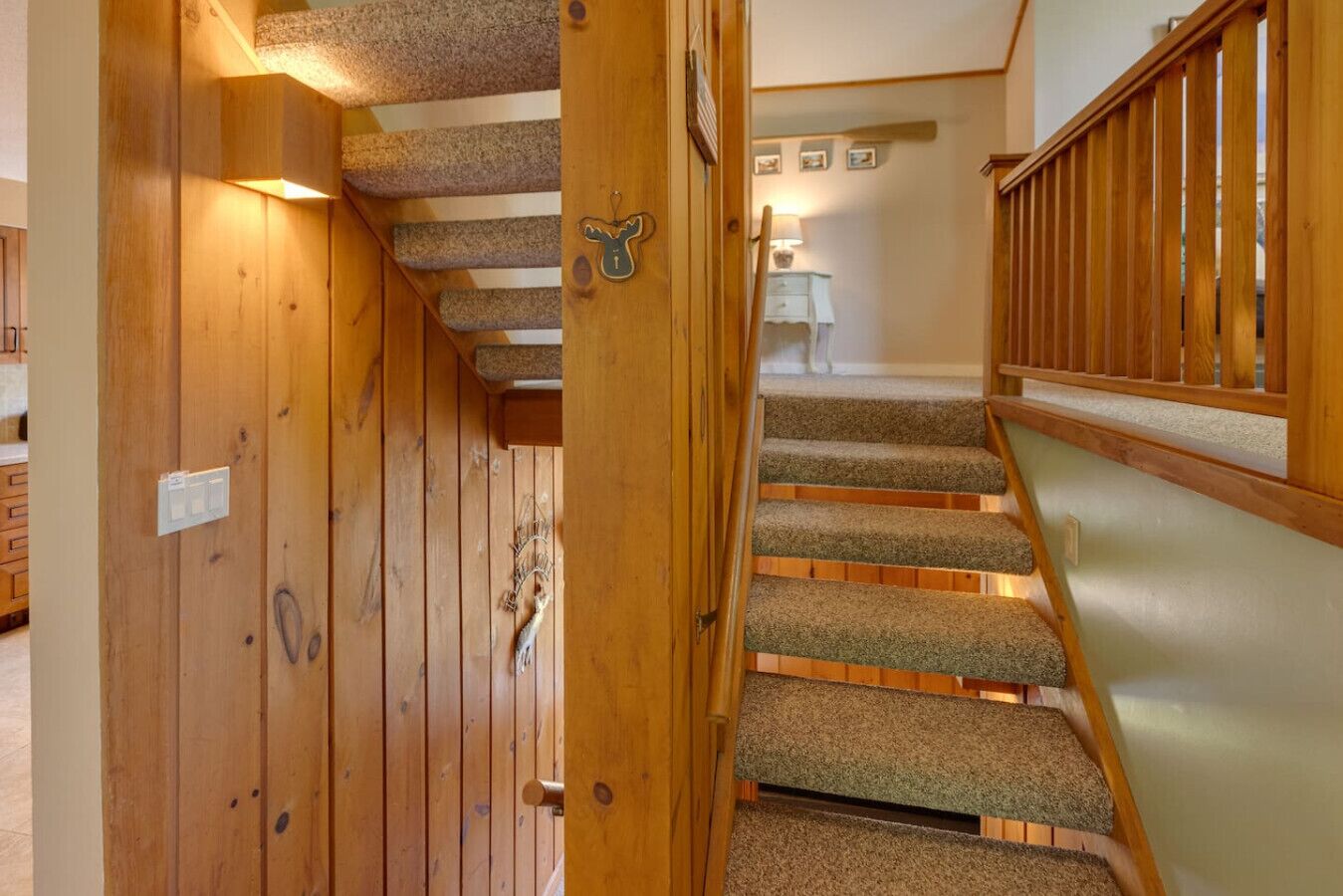 En trätrappa med steg som är klädda med matta, som leder upp till ett rum med en vit vägg och ett litet bord.