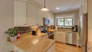 A modern kitchen with granite countertops, stainless steel appliances, and a large window providing natural light.