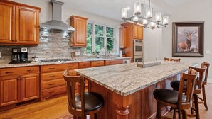 A spacious kitchen with wooden cabinets, a large island, and a stone backsplash. - Stunning Custom Home w/ Views (Lincoln)