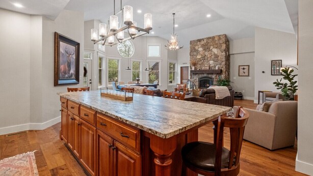 A spacious kitchen with a large island, wooden cabinets, and a stone fireplace. - Stunning Custom Home w/ Views (Lincoln)