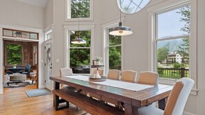 A spacious dining area with a long wooden table, multiple chairs, and pendant lighting. - Stunning Custom Home w/ Views (Lincoln)