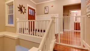 Una escalera con barandillas blancas y piso de madera que conduce a una habitación con una puerta y un cuadro enmarcado en la pared.