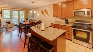 Una cocina con armarios de madera, encimera de granito, estufa de acero inoxidable y microondas.