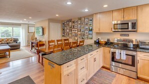 Una cocina moderna con armarios de madera, encimera de granito, electrodomésticos de acero inoxidable y una zona de comedor con una isla grande.