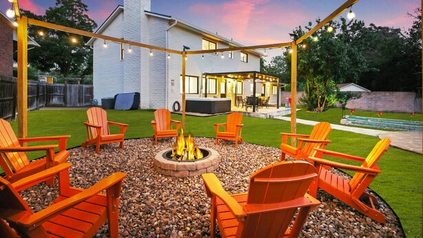 Un jardin avec un foyer, des sièges d’extérieur et une terrasse couverte.