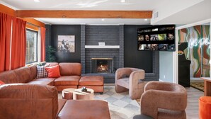 Un salon moderne avec une cheminée, des canapés en cuir et une bibliothèque.