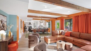Un salon moderne avec un canapé d’angle, une table basse en bois et un coin repas à l’arrière-plan.