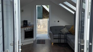 A compact living space with a kitchenette, a sofa, and a small table. - Modern Split-Level 2-Bed Apartment with Balcony (Causeway Coast and Glens)