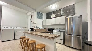 A compact kitchen with a central island, stainless steel appliances, and wooden stools.