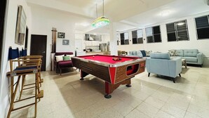 A spacious living area with a pool table, a sofa, and a dining table.