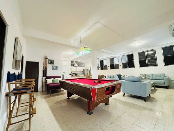 A spacious living area with a pool table, a sofa, and a dining table.