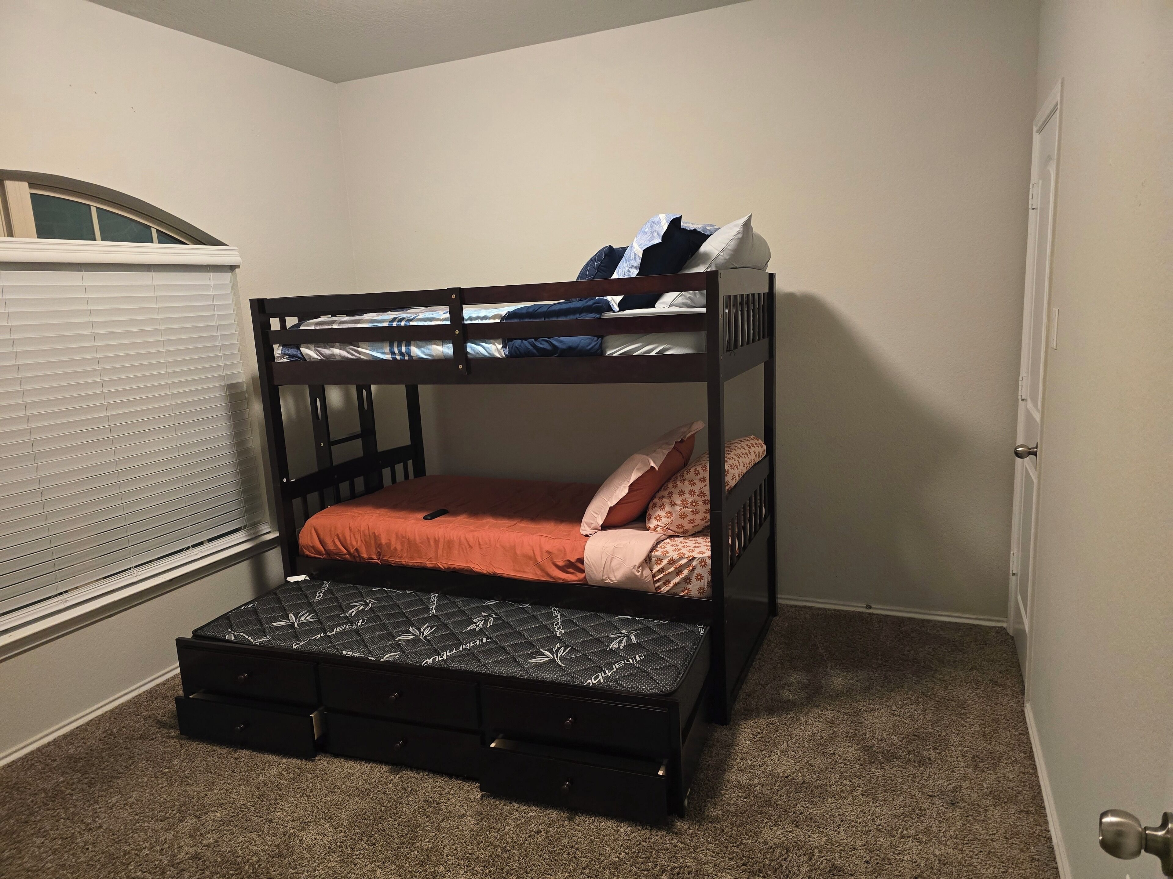 A bunk bed with a mattress on the lower bunk and a storage box underneath.