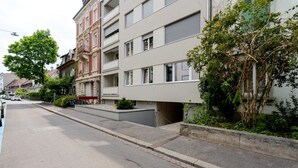 A residential street with multi-story buildings, a clear road, and parked bicycles. - Blueground | Basel-Iselin, view, nr Rhine (Basel)