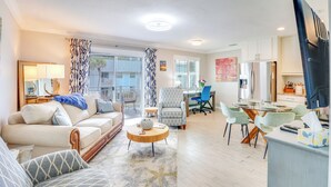 A spacious living room with a sofa, armchairs, a coffee table, and a dining area with a table and chairs.