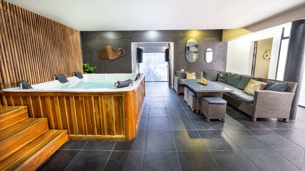 A modern spa area with a wooden hot tub, wicker furniture, and dark tiled flooring. - 6 Bedoom Apartment with Balcony, Pool tableJacuzzi (Medellín)