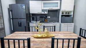 A dining area with a wooden table and black chairs, a decorative golden tree centerpiece, and a modern kitchen in the background. - 6 Bedoom Apartment with Balcony, Pool tableJacuzzi (Medellín)