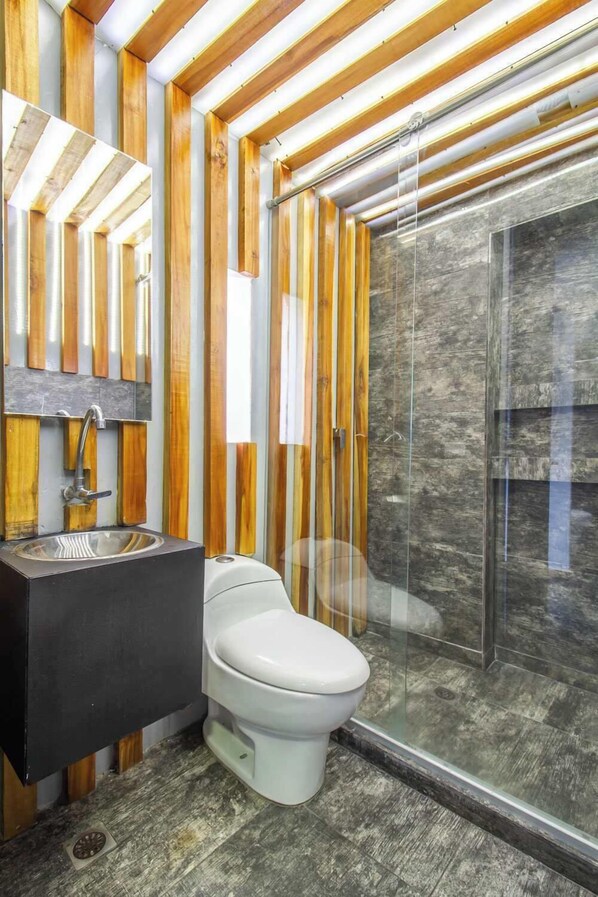 A modern bathroom with a wooden ceiling, a glass shower enclosure, and a white toilet.