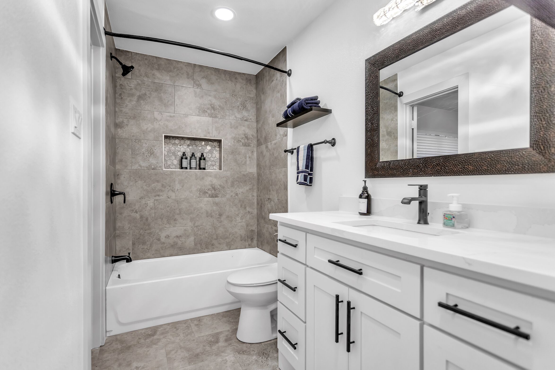 A modern bathroom with a bathtub, toilet, and vanity.