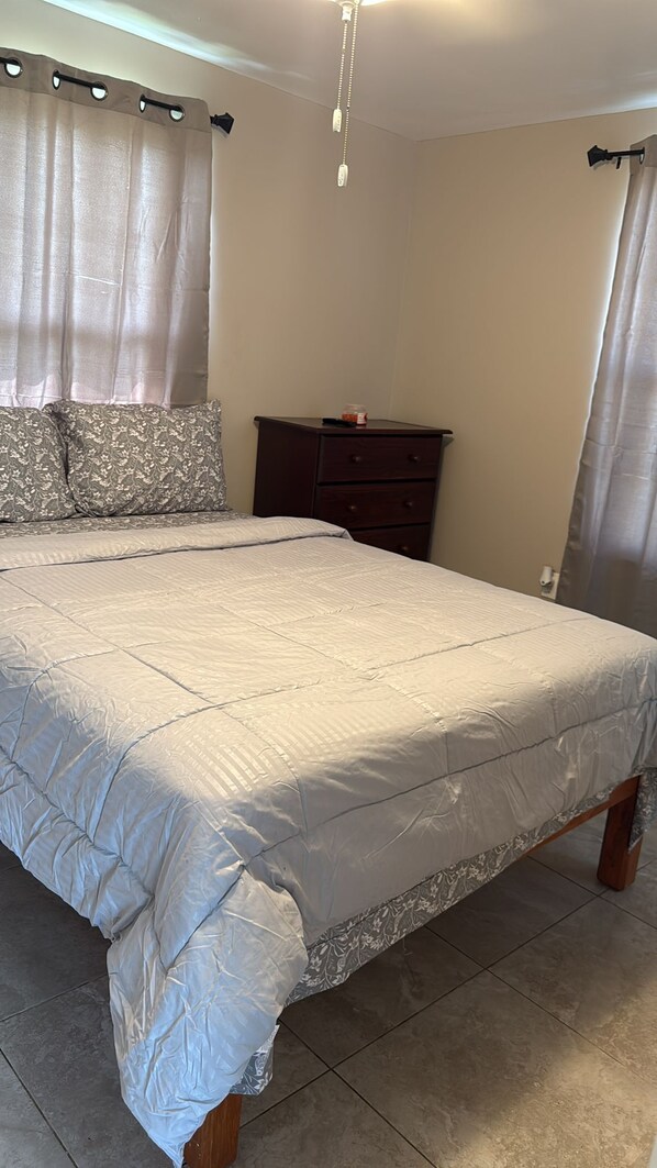 Un dormitorio con una cama grande, un aparador y cortinas.