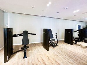 A fitness area with exercise equipment, including a rowing machine, a stationary bike, and a weight bench.