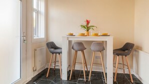 A small kitchen with a white table, three grey chairs, and a potted plant. - Two bedroom house with free parking, near city centre, sleeps up to five (Edinburgh)