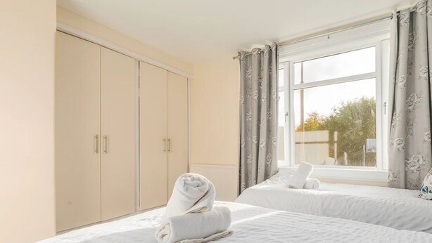 A hotel room with two beds, a wardrobe, and a large window with curtains. - Two bedroom house with free parking, near city centre, sleeps up to five (Edinburgh)