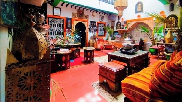 A vibrant interior with a red floor, ornate metalwork, and a balcony with colorful railings. - Authentic Riad in Marrakech - A Living Museum of Moroccan Art (Marrakech)