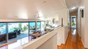 Un interior moderno con comedor que ofrece vistas panorámicas, una cocina con armarios blancos y suelo de madera.